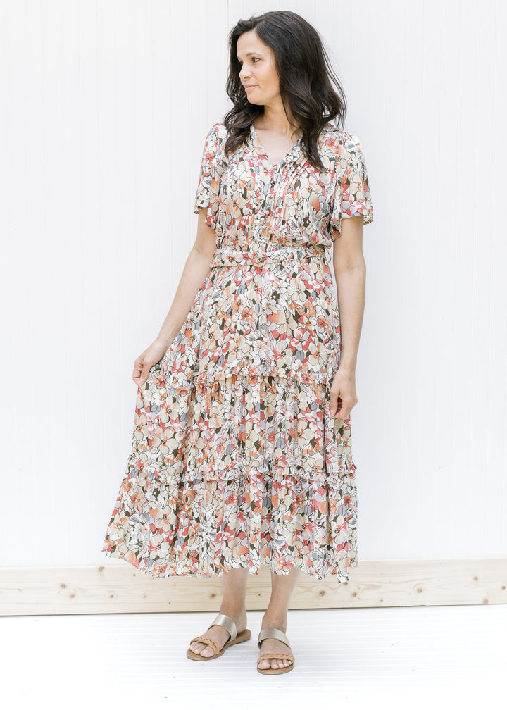 Model wearing a midi dress featuring a neutral floral pattern with an elastic waistband and a belt. 