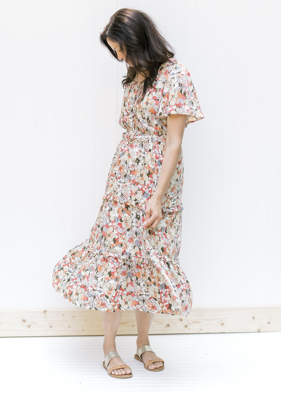 Model wearing a midi v-neck dress with a neutral floral pattern, flutter short sleeves and a belt. 