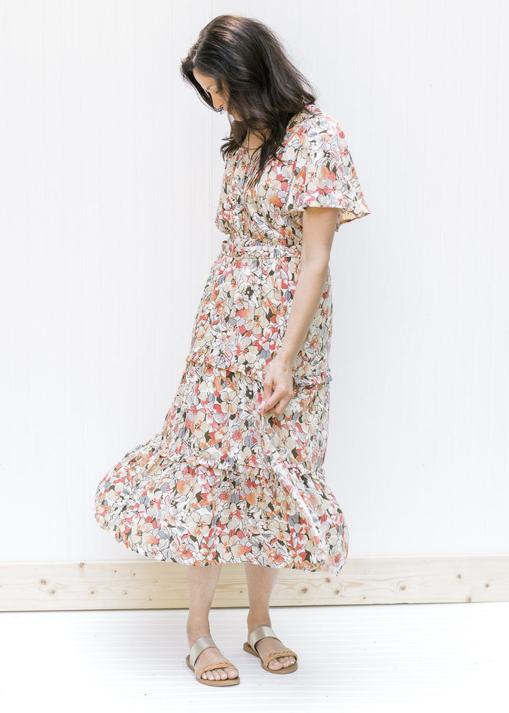 Model wearing a midi v-neck dress with a neutral floral pattern, flutter short sleeves and a belt. 