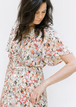 Model wearing a neutral floral midi dress with flutter short sleeves and a button up v-neck. 