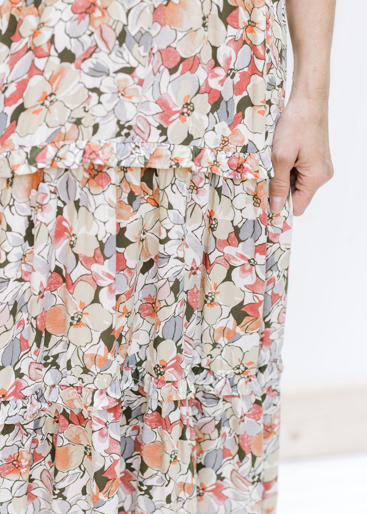 Close up view of ruffle details on the tiers of a neutral color midi dress made of rayon. 