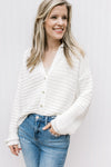 Model wearing a cream button up cardigan with bubble long sleeves, ribbed material and a collar. 