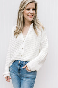 Model wearing a cream button up cardigan with bubble long sleeves, ribbed material and a collar. 