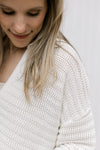 Close up of ribbed knit material on a cream button up cardigan with bubble long sleeves.