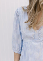 Close up of placket on the bodice of a v-neck tone on tone checkered dress with 3/4 length sleeves.