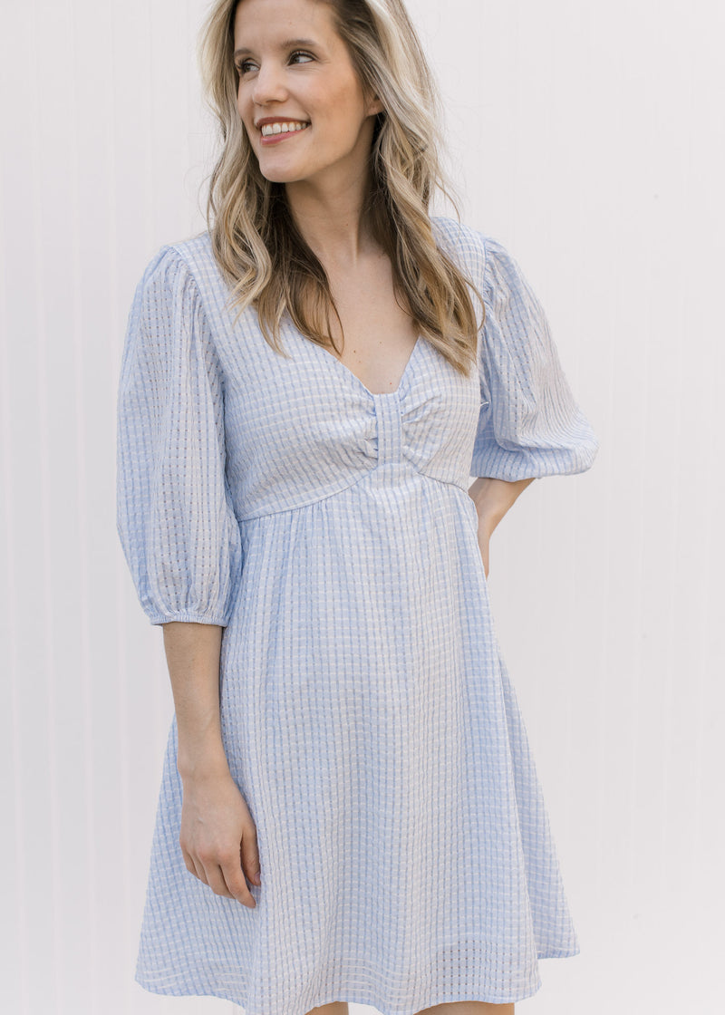 Model wearing a tone on tone checkered above the knee dress with a placket at bodice.
