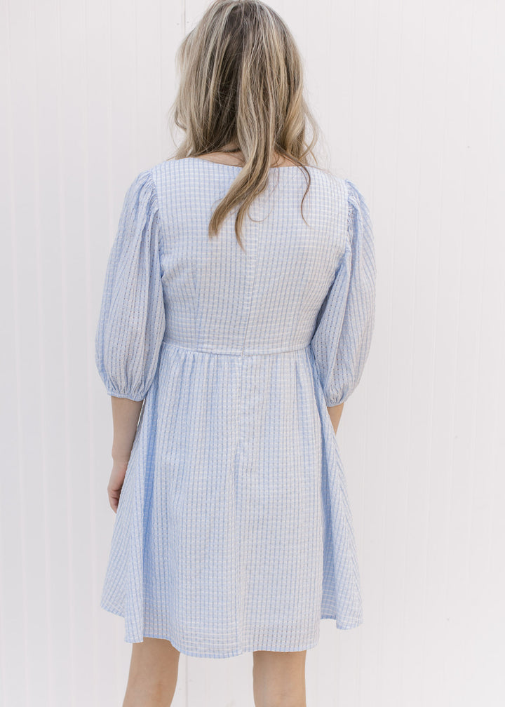 Back view of Model wearing a tone on tone checkered above the knee dress with a placket at bodice.