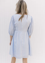 Back view of Model wearing a tone on tone checkered above the knee dress with a placket at bodice.