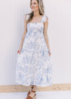 Model wearing heels with a white tiered midi with blue floral, tie straps and a square neck