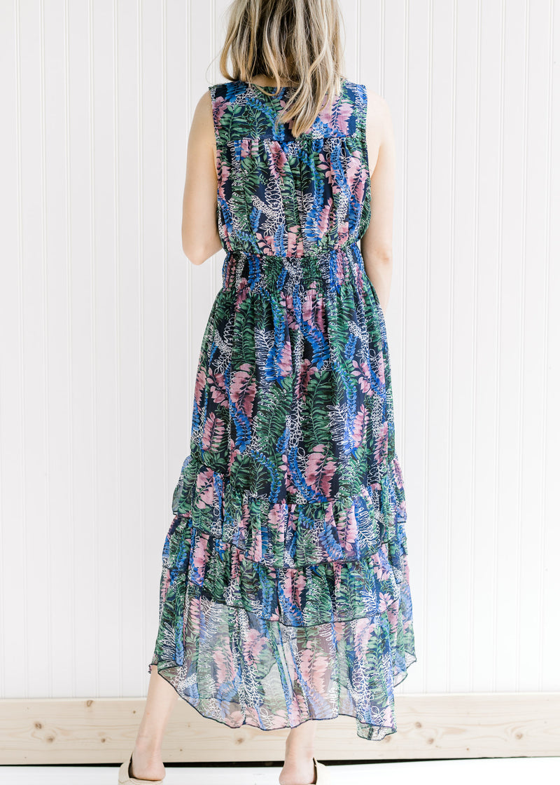 Back view of a model wearing a sleeveless maxi with a floral pattern and an elastic waist. 