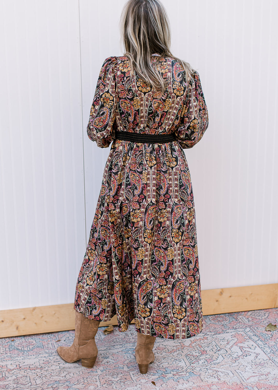 Back view of Model wearing a black midi with warm fall floral, 3/4 bubble sleeves  and long sleeves.