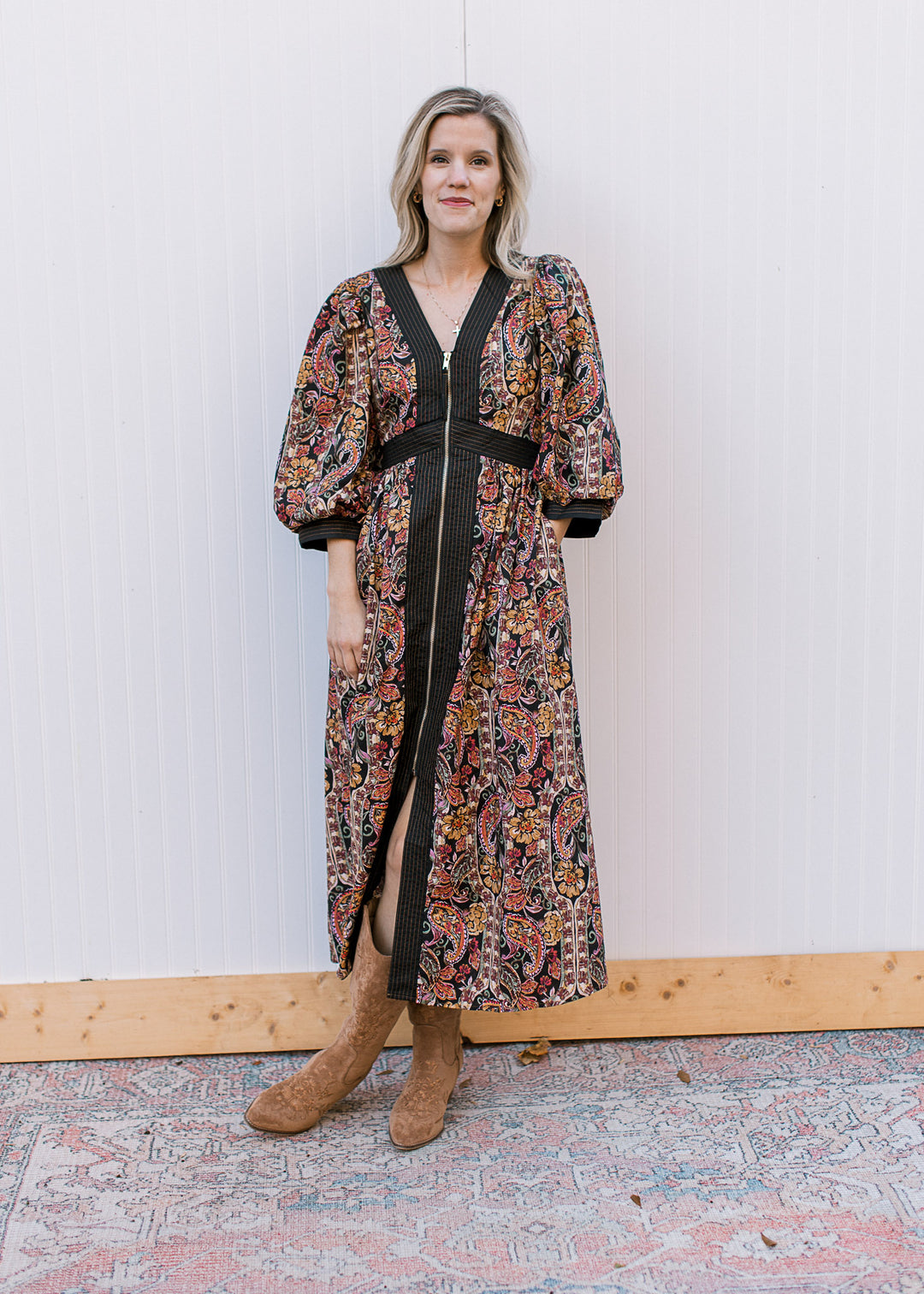 Model wearing a black midi with warm fall floral, 3/4 bubble sleeves, pockets and long sleeves.