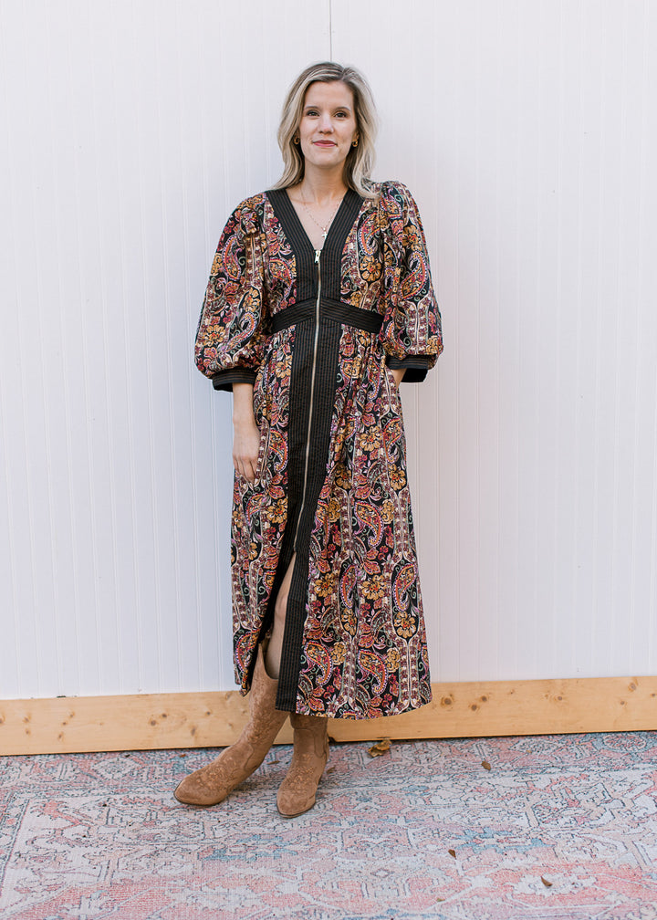 Model wearing a black midi with warm fall floral, 3/4 bubble sleeves, pockets and long sleeves.