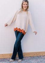 Model wearing booties, jeans and a cream top with rust ric-rac hem and a round neck.