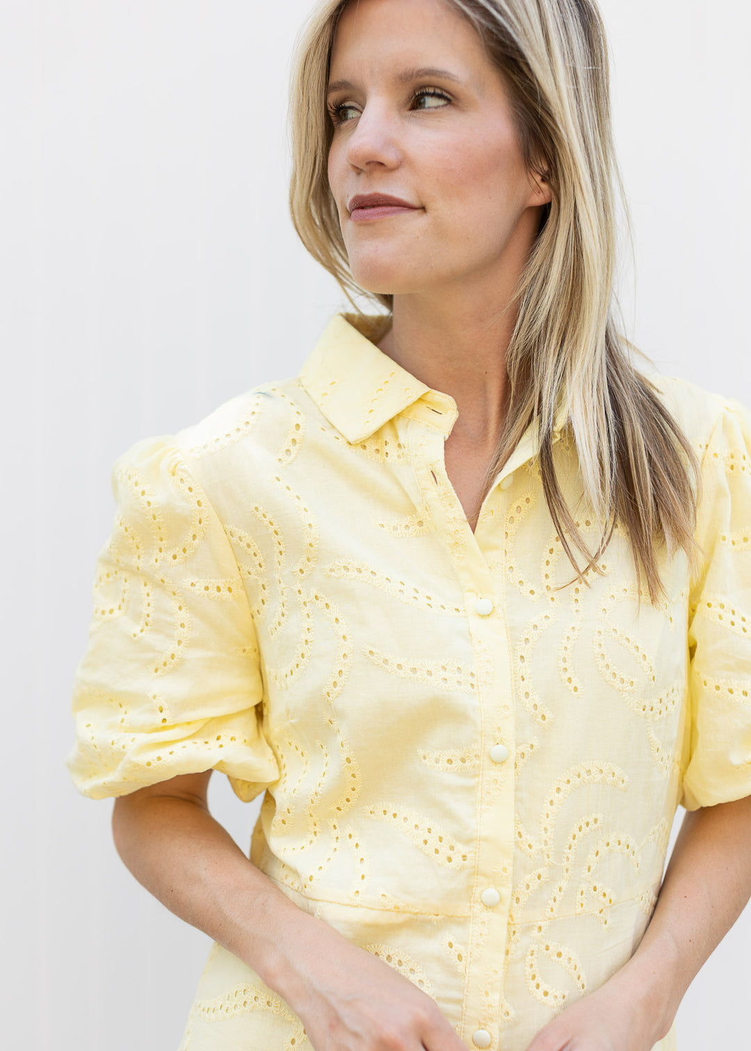 Close up of button front, collar and eyelet detail on a yellow dress with bubble short sleeves. 