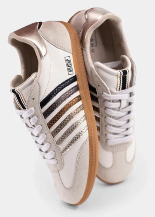Side and top view of faux suede cream sneakers with silver, bronze, copper, and gold strips. 