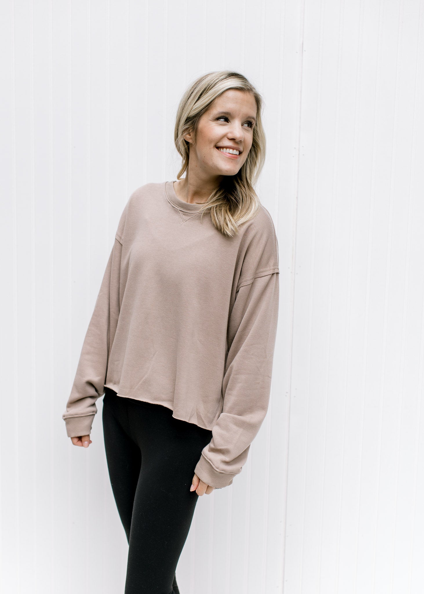 Model wearing leggings with a stone sweatshirt with a raw hemline, exposed hem and long sleeves.