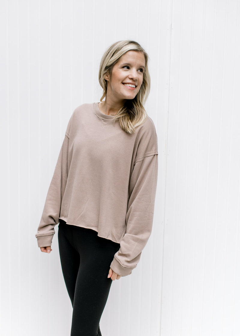 Model wearing leggings with a stone sweatshirt with a raw hemline, exposed hem and long sleeves.
