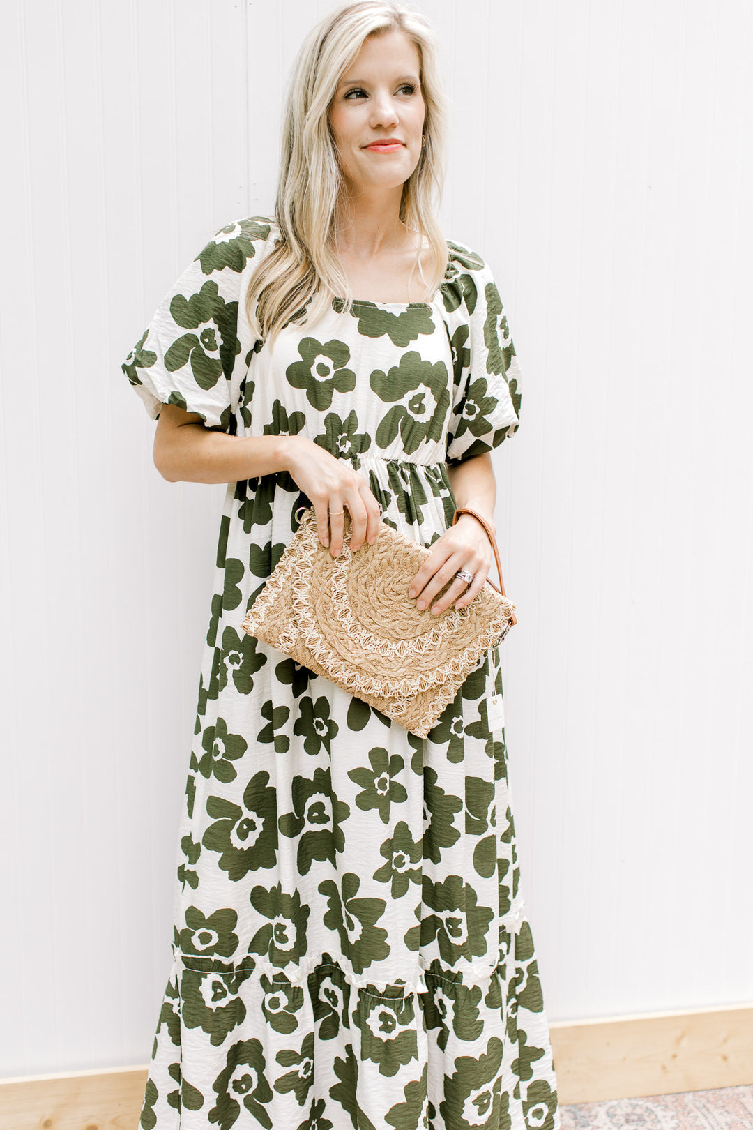 Model holding a taupe and white straw clutch bag. 
