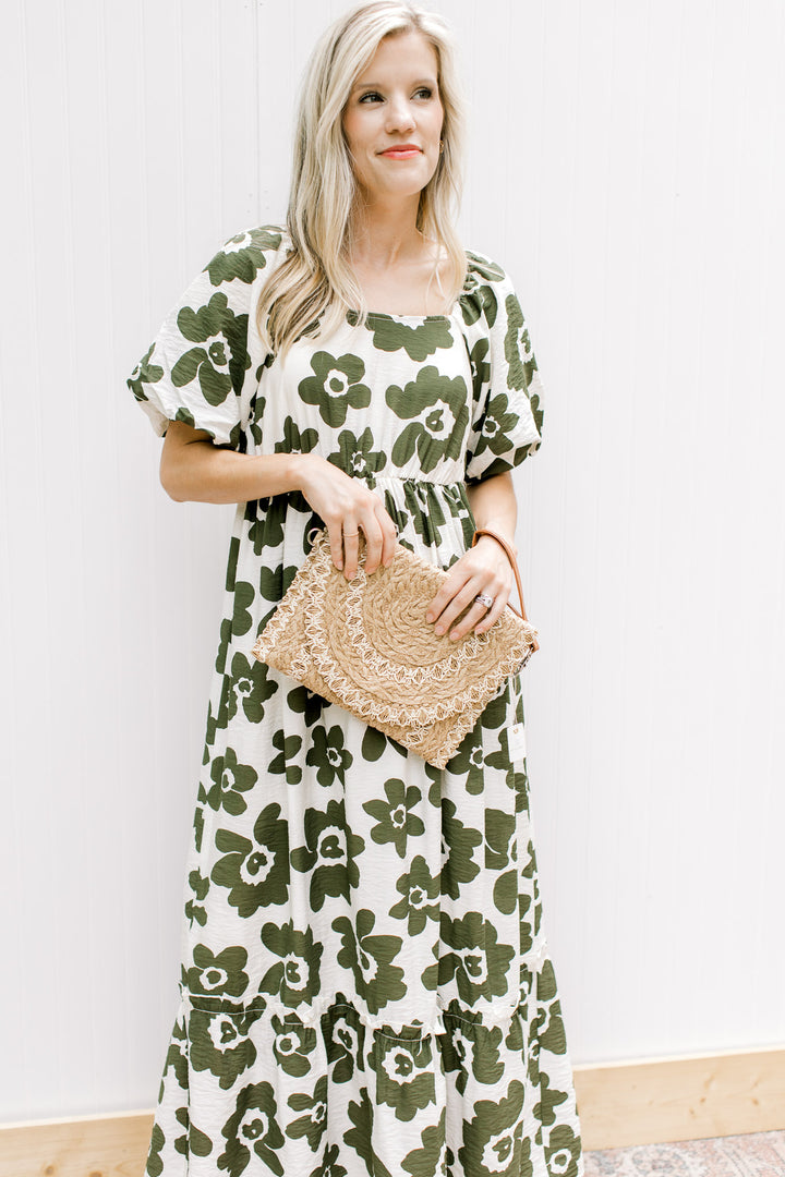 Model holding a taupe and white straw clutch bag. 