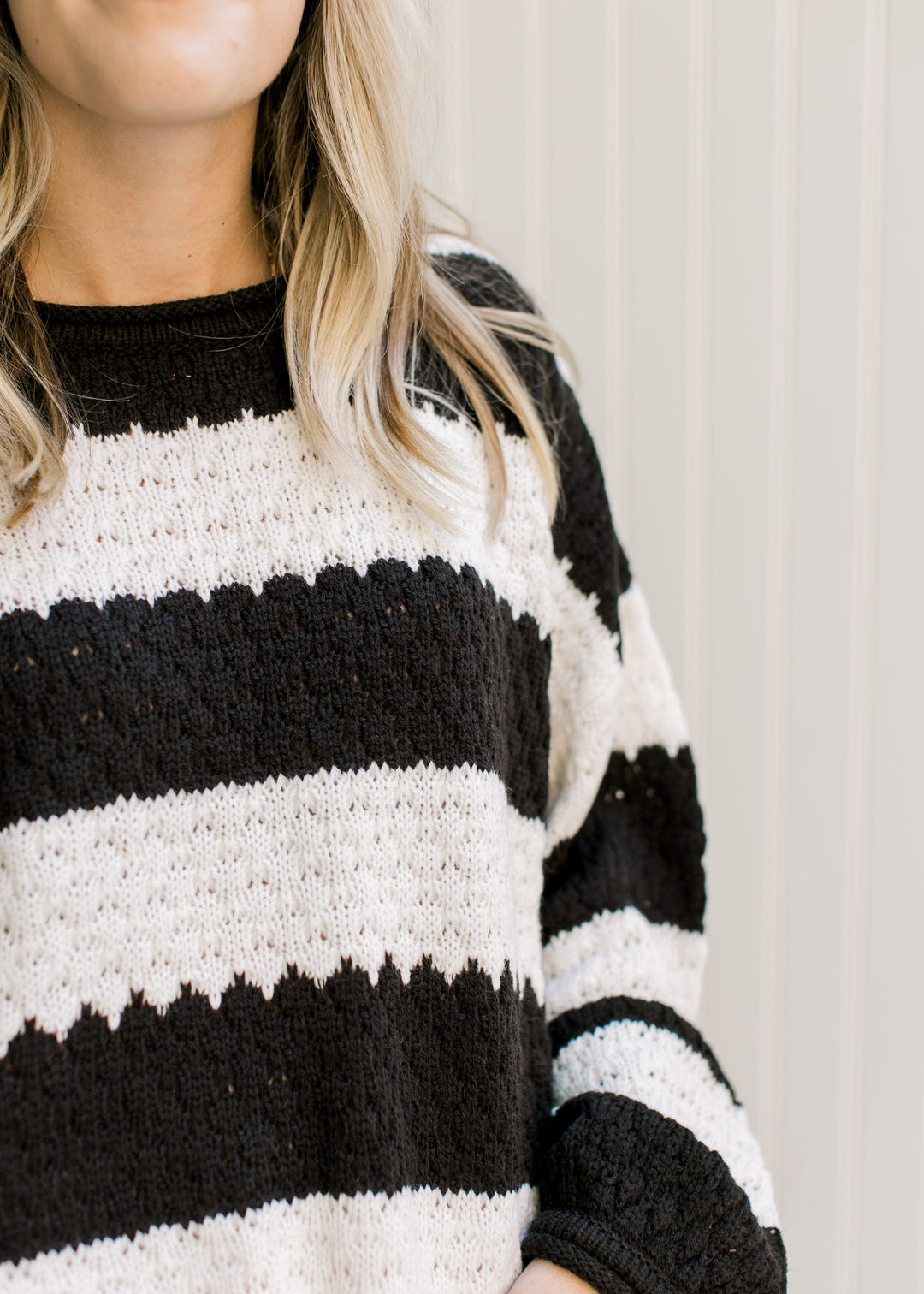 Close up of knit fabric and round neck on a black and white long sleeve striped sweater. 