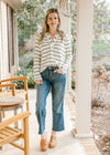 Model wearing jeans, mules and a cream top with olive stripes, long sleeves and a v-neck. 