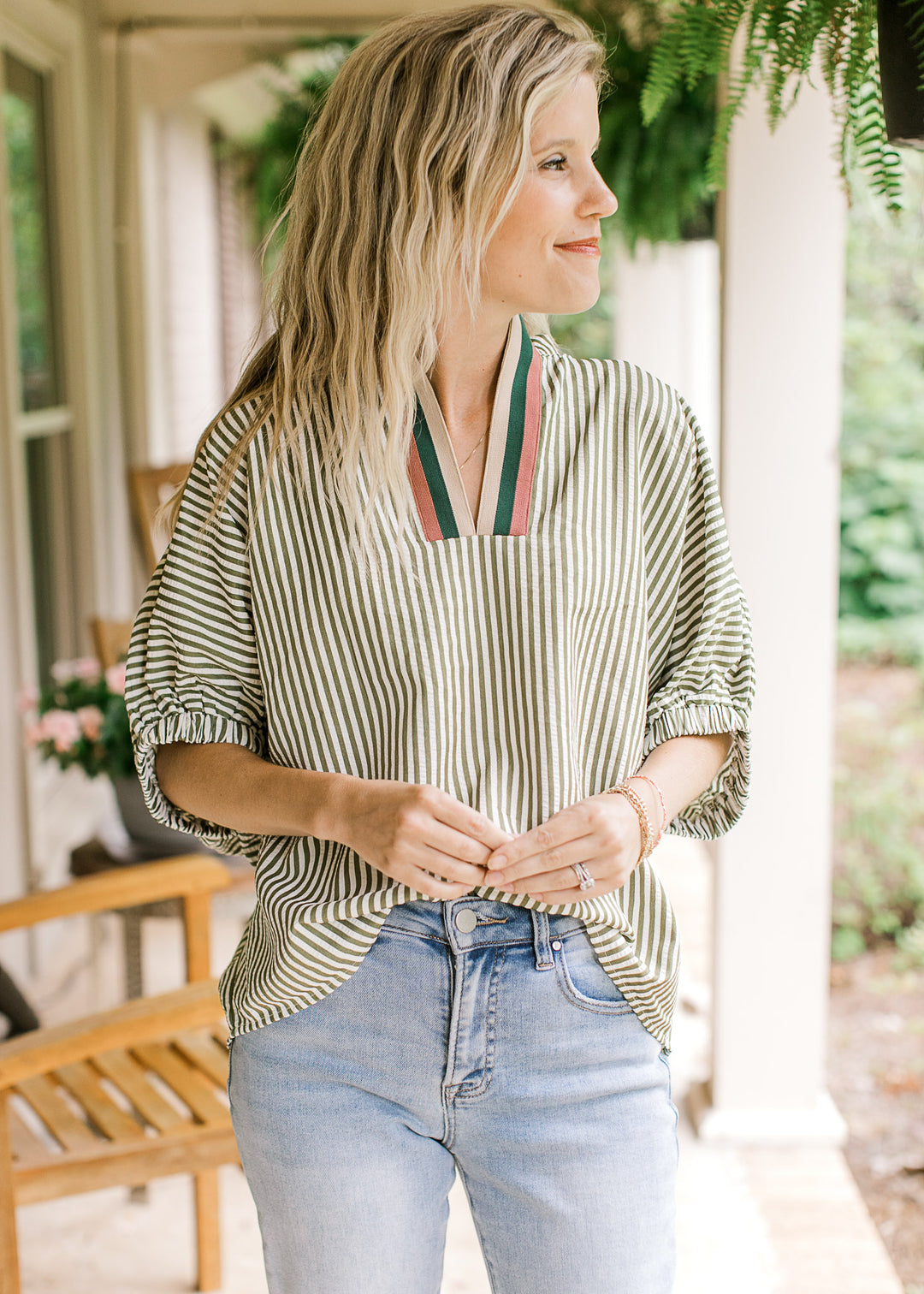 Model wearing an olive and cream striped top with extended short sleeves with elastic at hem. 