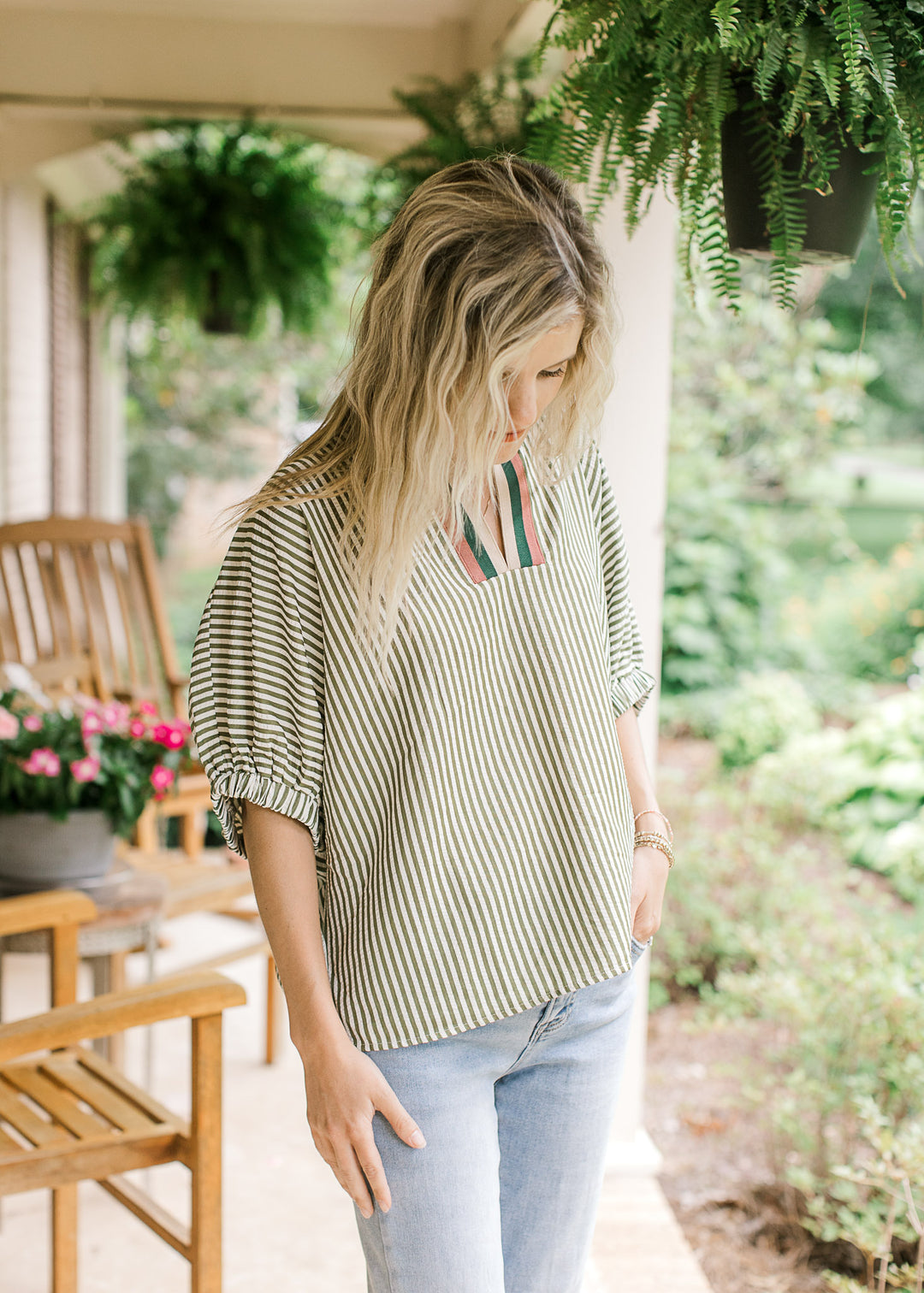 Model wearing jeans and a short sleeve olive and cream striped top with v-neck and short sleeves.
