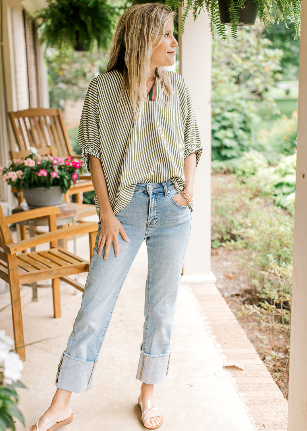 Model wearing jeans, sandals and a short sleeve olive and cream striped top with short sleeves.