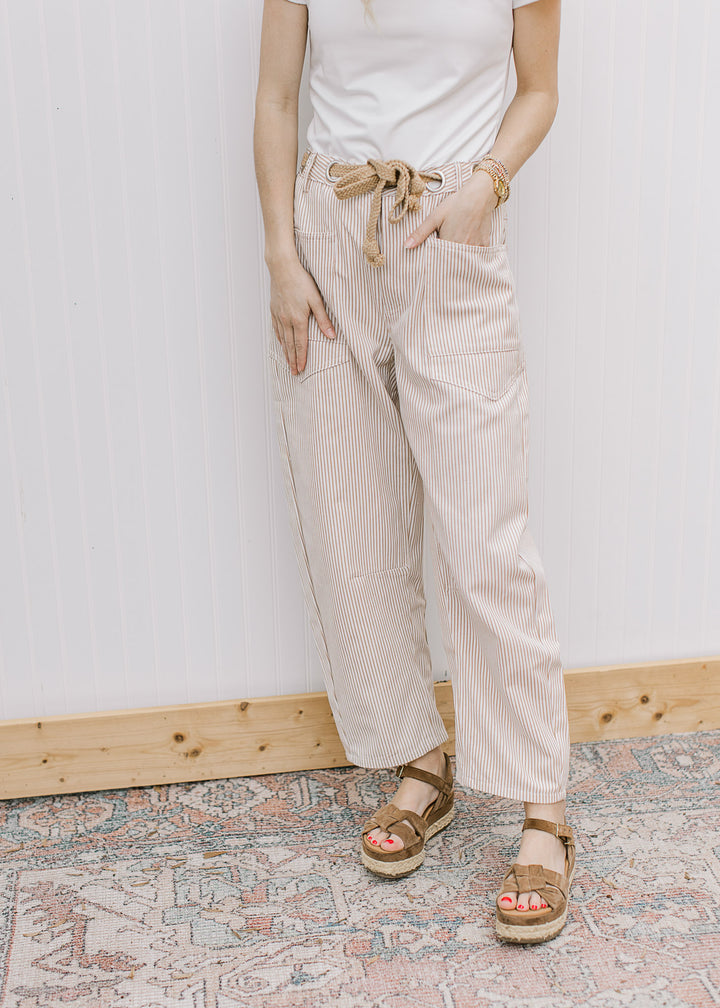 Model wearing cream barrel leg pants with tan stripes, high waist, ankle length and patch pockets.