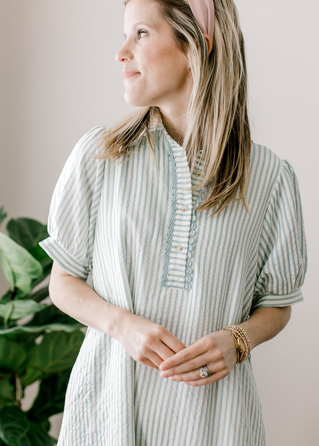 Model wearing a sage blue and cream stripe dress with short sleeves, v-neck and a button placket.