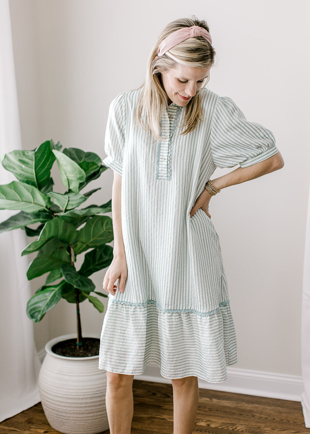 Model wearing a short sleeve sage blue and cream stripe dress with v-neckline and collar. 
