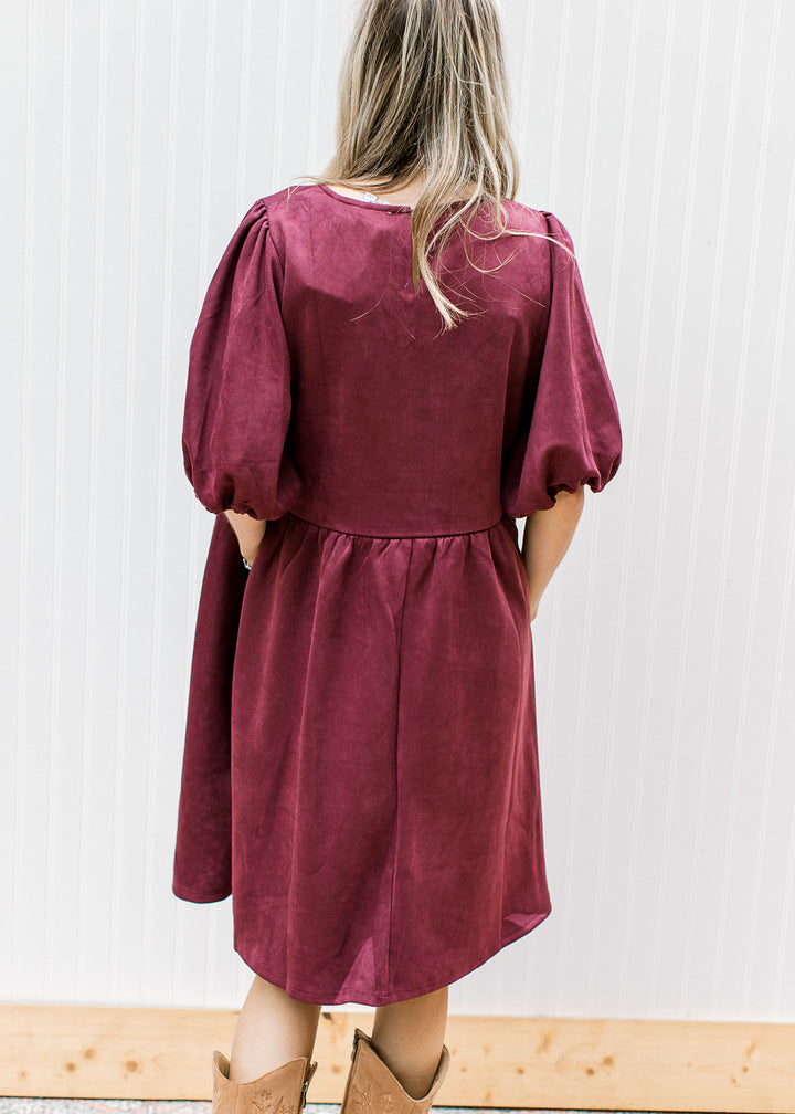 Back view of a suede burgundy above the knee dress with bubble 3/4 sleeves and pockets. 