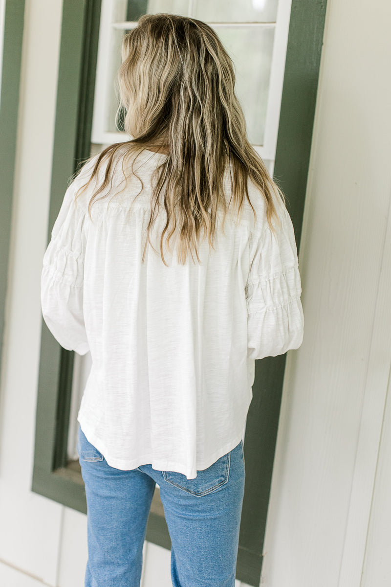 Back view of Model wearing a cotton white top with 3/4 sleeves and a v-neck with ties.