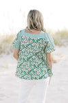 Back view of Model wearing a mixed green floral pattern top with a square neck and short sleeves. 