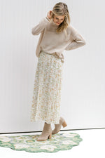 Model wearing cream top with a white maxi skirt with a cream floral pattern and elastic waistband. 