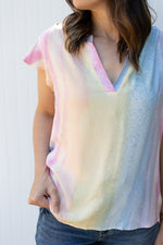 Close up of v-neck and flutter cap sleeves on a bright ombre top.