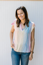 Model wearing jeans with a bright ombre top with a v-neck and flutter cap sleeves.