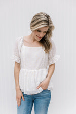 Model wearing jeans and a white top with white and yellow daises, a square neck and short sleeves.