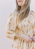 Close up of square neck, Smocked bodice and 3/4 bubble sleeves on a pale yellow floral dress. 