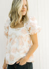 Model wearing a white and coral embroidered floral top with a square neck and bubble short sleeves. 