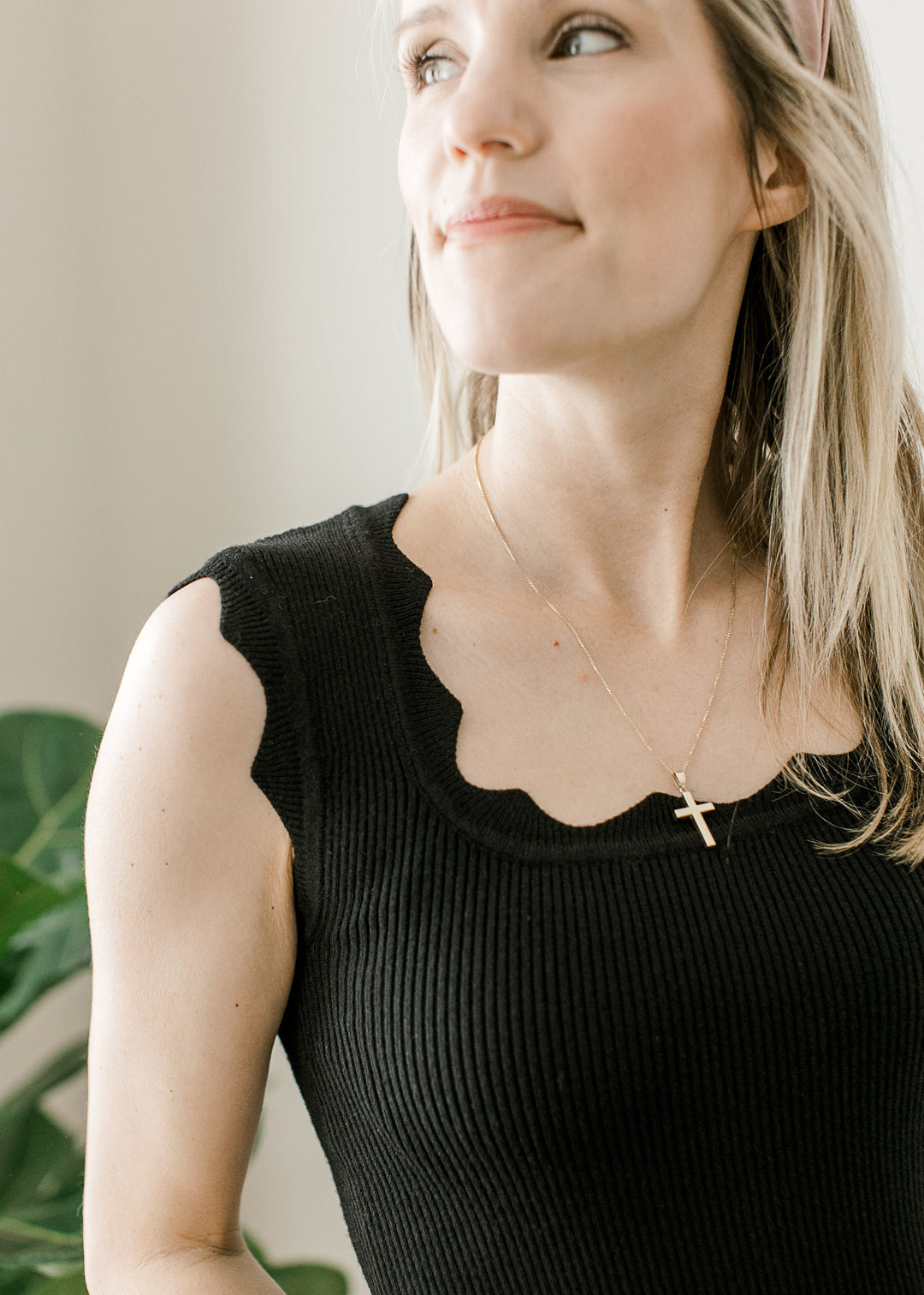 Model wearing a black ribbed top with scalloped square neck and at sleeveless straps. 