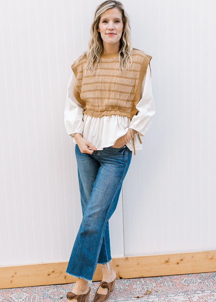 Model wearing jeans and a long sleeve cream blouse with a caramel and cream attached vest. 