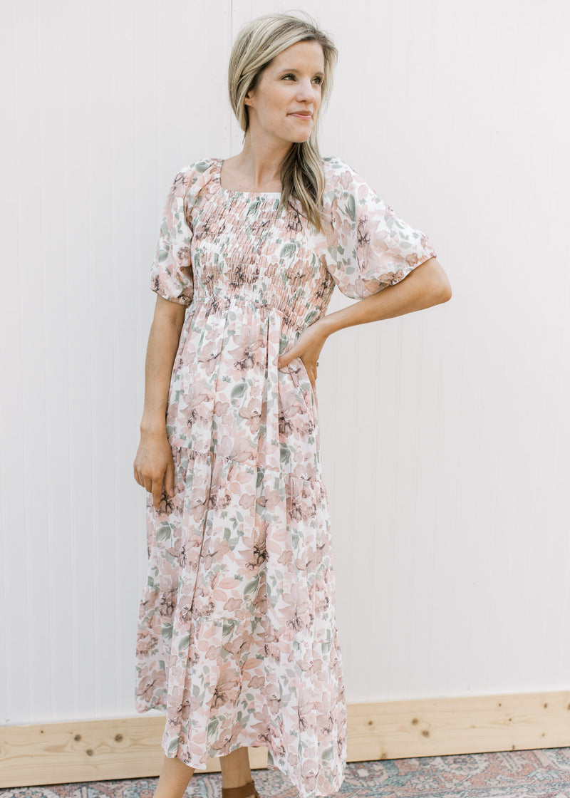 Model wearing a cream midi with pink flowers, smocked bodice and a square neck.