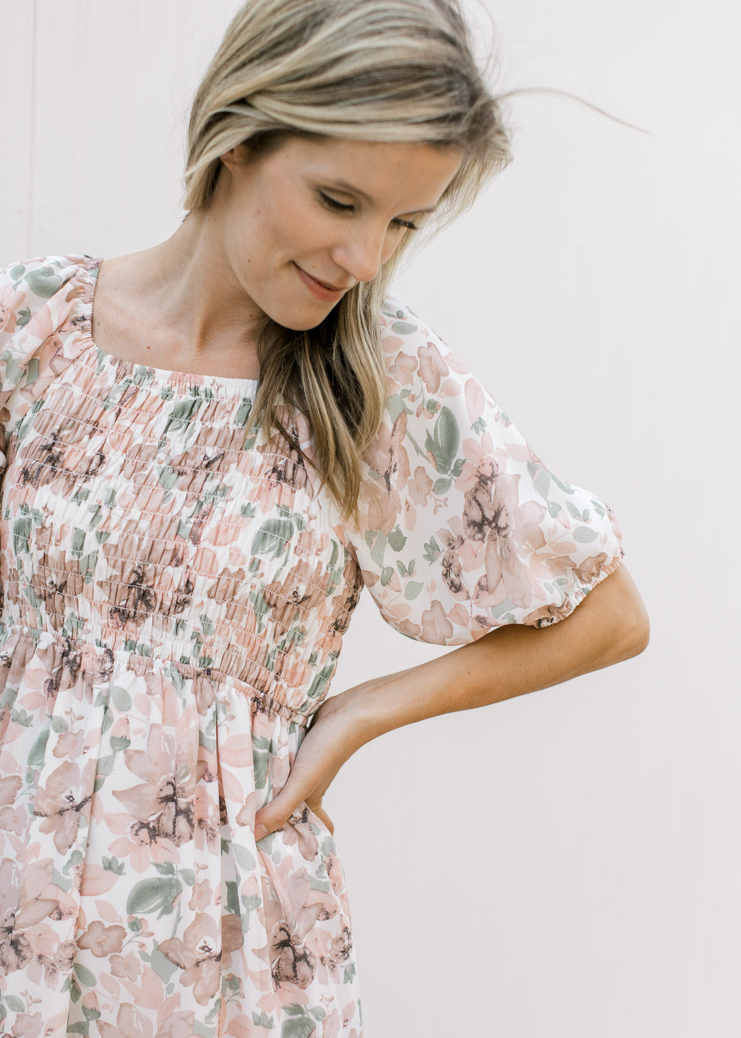 Close up of smocked bodice and short puff sleeves on a cream midi with pink flowers.