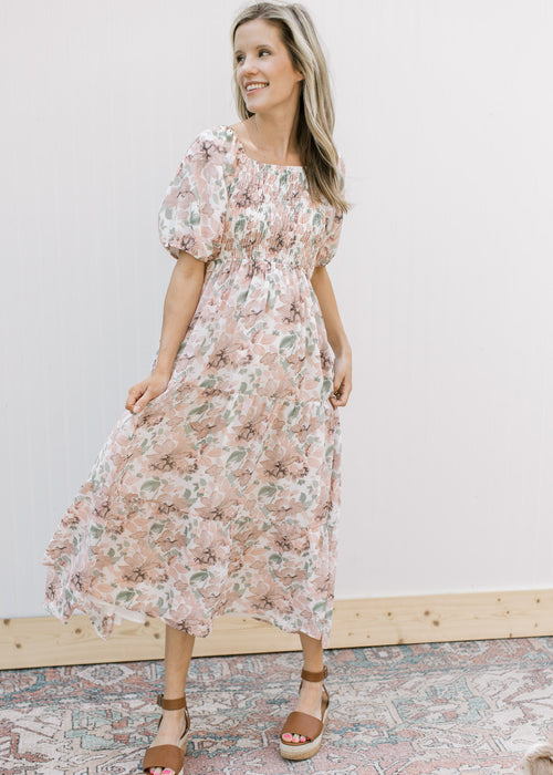 Model wearing a cream midi with pink flowers, smocked bodice and short puff sleeves. 