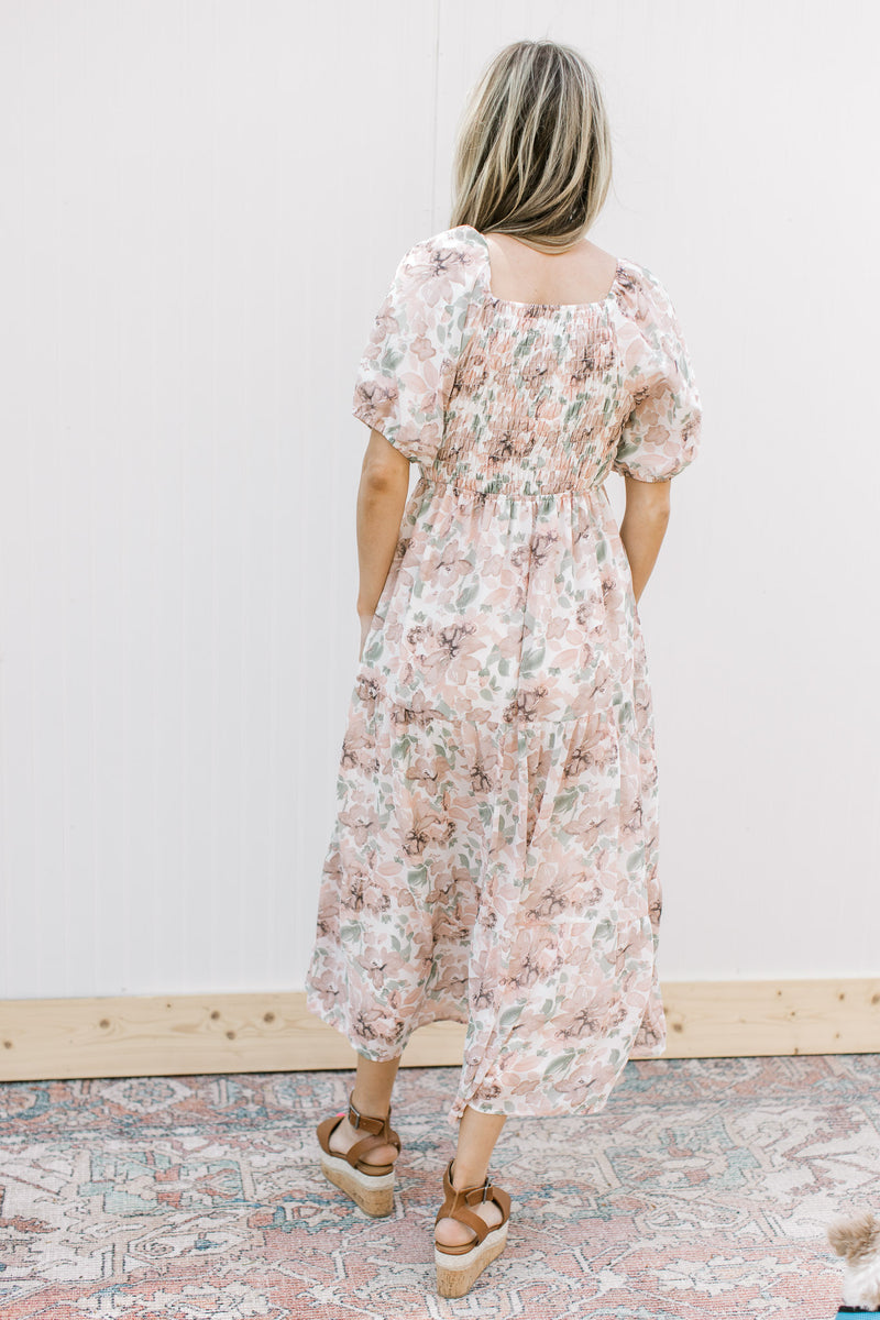 Back view of Model wearing a cream midi with pink flowers, smocked bodice and short puff sleeves.