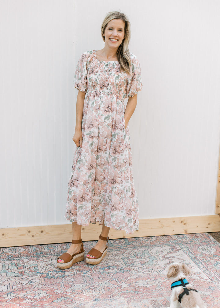 Model wearing heels with a cream midi with pink flowers, smocked bodice and short puff sleeves.