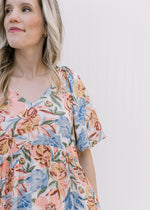 Close up of v-neck and bubble short sleeves on a white dress with peach, blue and mustard flowers.