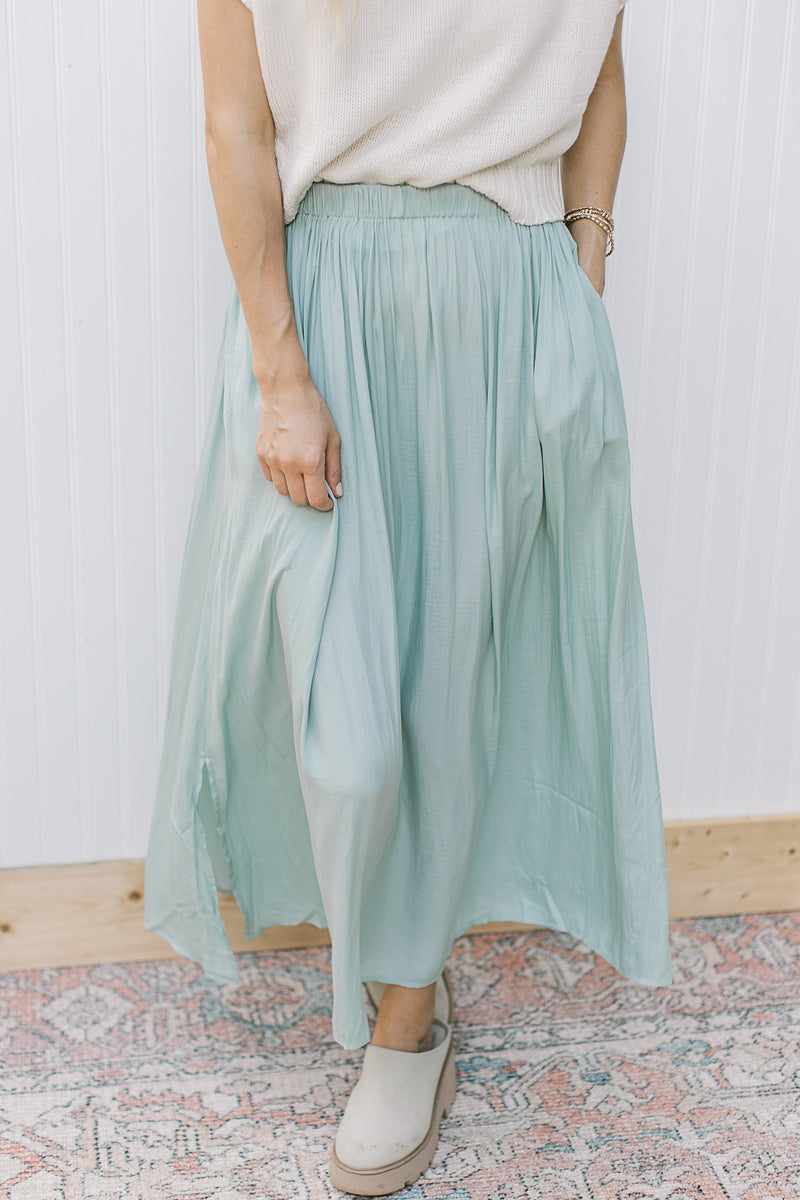 Model wearing a sage polyester midi with a flowy fit and an elastic waist. 